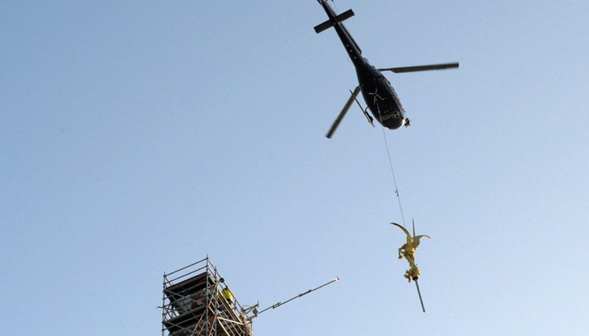 Helicopter lifts the statue of Archangel Michael from top of Mont Saint-Michel Abbey for maintenance