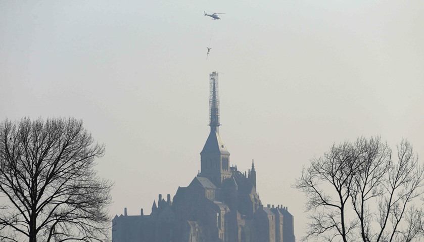 Helicopter lifts the statue of Archangel Michael from top of Mont Saint-Michel Abbey for maintenance