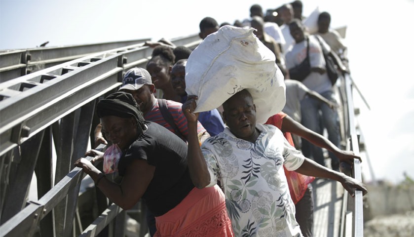 Haitians cross the collapsed bridge