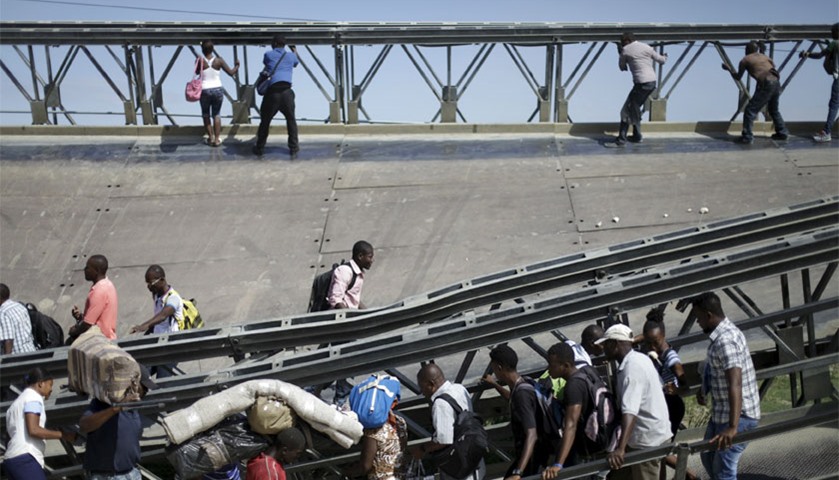 Haitians cross the collapsed bridge