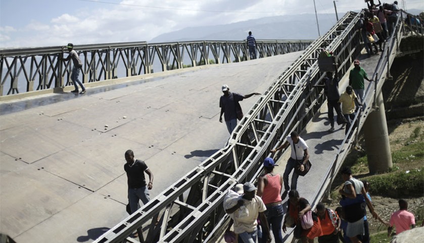 Haitians cross the collapsed bridge on the outskirts of Port-au-Prince, Haiti. The bridge collapsed 