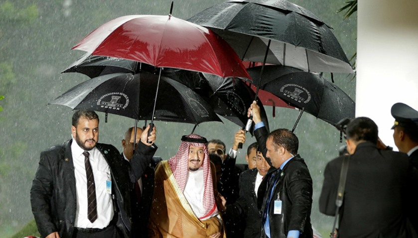 Saudi Arabia\'s King Salman and Indonesian President Joko Widodo walk under umbrellas in heavy rain