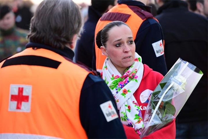 A woman holding a bunch of flowers waits at Brussels international airport