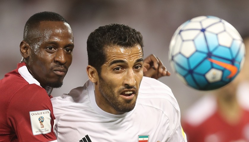 Iran\'s Vahid Amiri (R) and Qatar\'s Yasir Isa vie for the ball