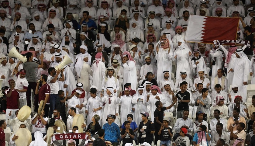 Qatari fans wave their national flag as they cheer