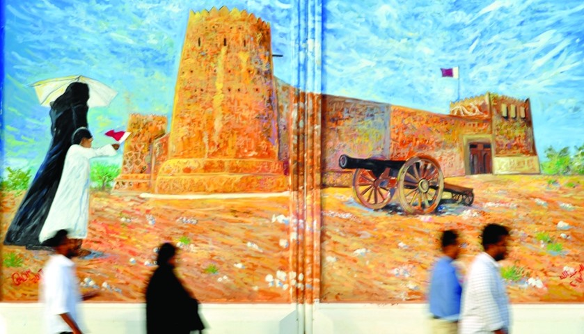 Visitors walk past one of the murals depicting the renowned Al Zubarah Fort.
