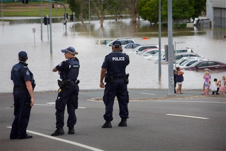 Queensland police officers keep a watch over submerged cars at a car park