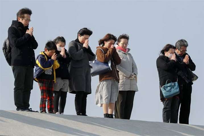 People offer one-minute prayer for victims killed by tsunami, at Arahama district, Miyagi prefecture