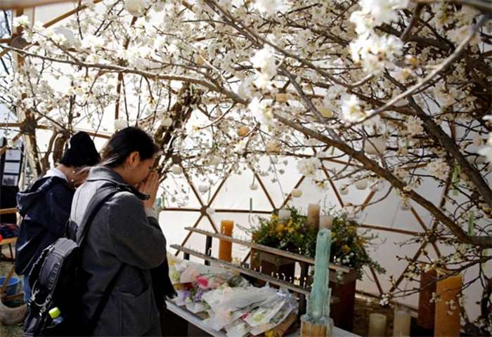 Women pray for victims of the March 11, 2011 earthquake and tsunami, at a park in Tokyo on Sunday