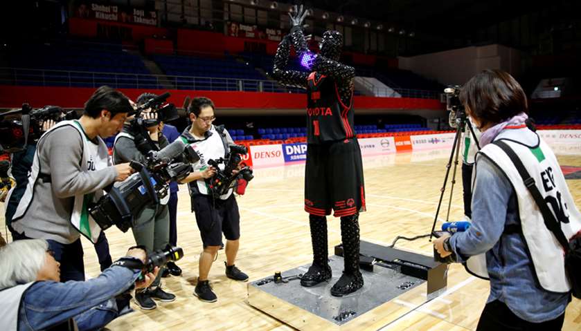 Members of the media film a basketball-playing robot called CUE, developed by Toyota engineers, duri