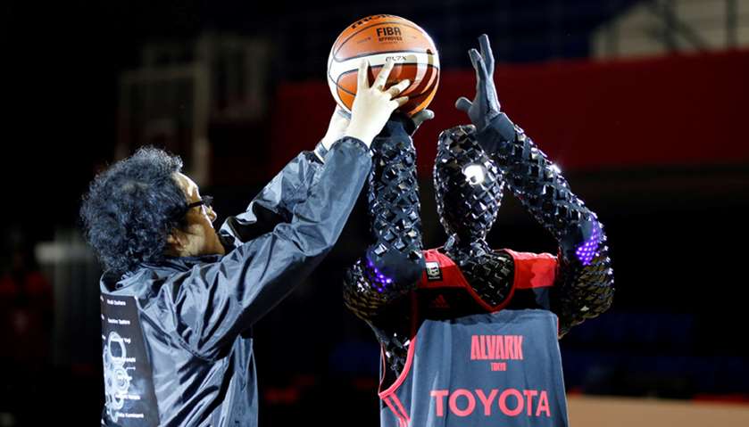 An engineer sets a ball to a basketball-playing robot called CUE, developed by Toyota engineers