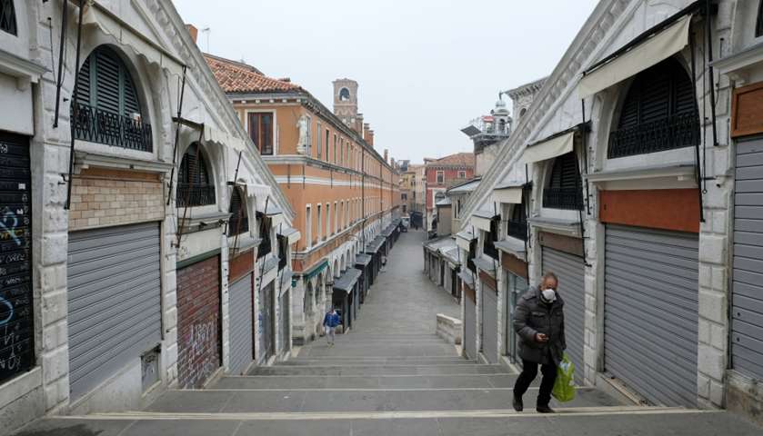 A man wearing a protective mask crosses the Rialto Bridge in Venice