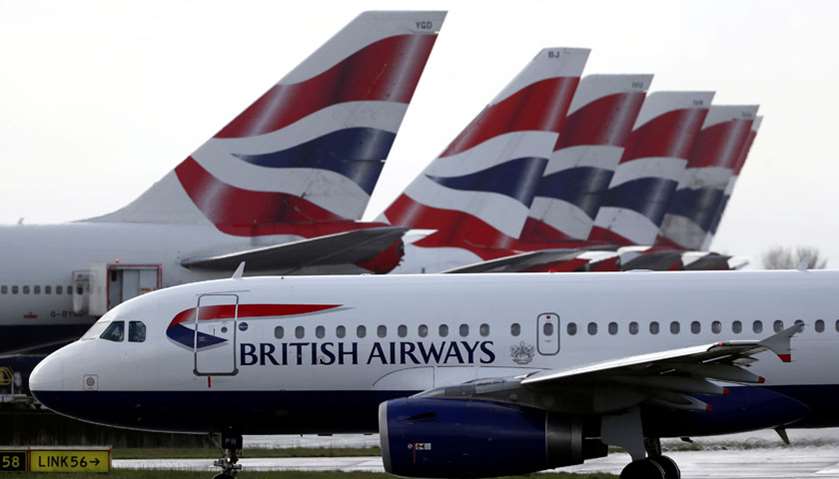 A British Airways plane taxis past tail fins of parked aircraft to the runway near Terminal 5 at Hea