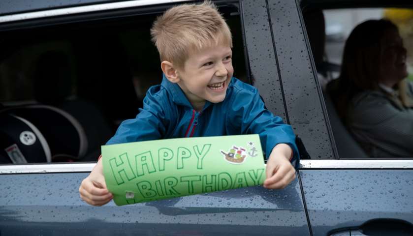 Anderson Moore, 5, wishes his neighbor Kellen Shea, 3, happy third birthday from a caravan of cars
