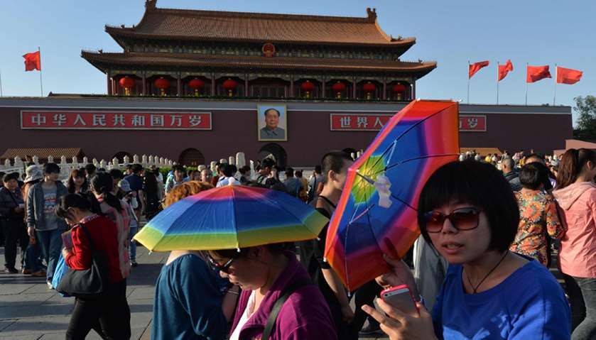 Tourists walking past a portrait of Mao Zedong at Tiananmen Square in Beijing
