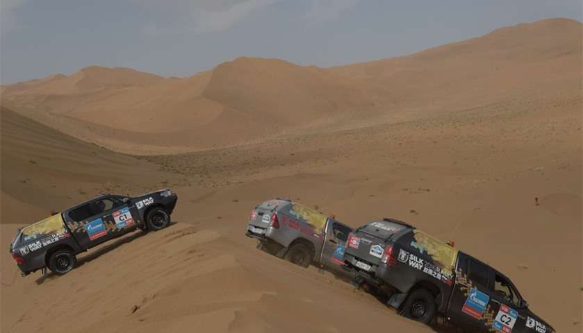 Cars drive over sand dunes