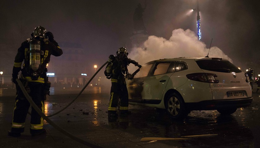 French firefighters take action on a police car set on fire at Place de la Republique