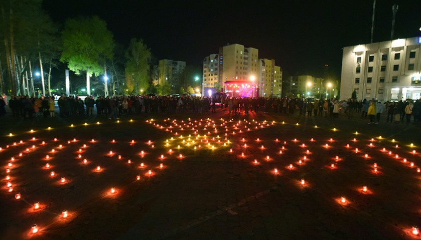 Candles set in the shape of a radiation hazard symbol is seen on a square next to the monument to Ch