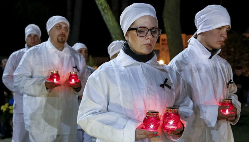 Staff of the Chernobyl nuclear plant hold candles as they visit a memorial