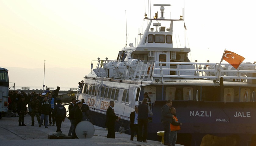 Migrants board a Turkish-flagged passenger boat to be returned to Turkey