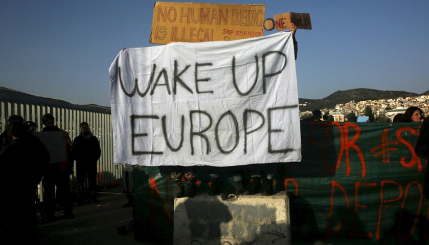 Activists hold banners as they protest against the return of migrants to Turkey