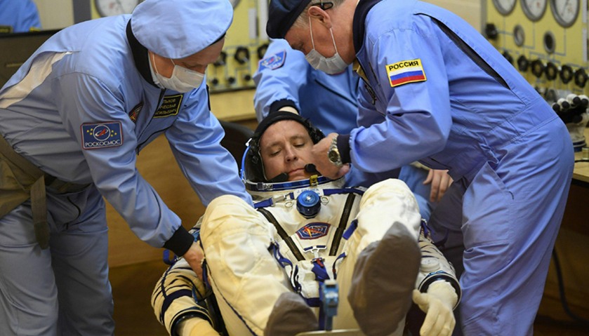 NASA astronaut Jack David Fischer (C) has his spacesuit tested
