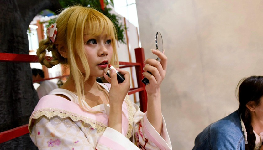 a cosplay fan putting on her makeup as she attends the China International Cartoon and Animation Fes