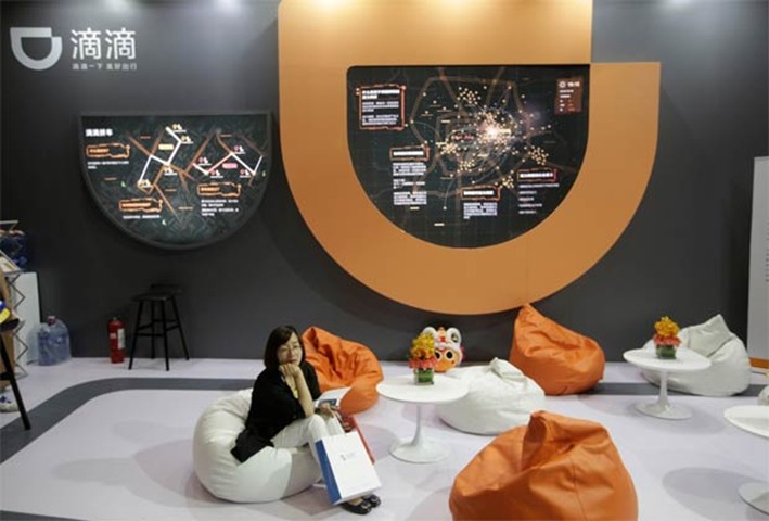 A woman sits at Didi Chuxing\'s booth at the Global Mobile Internet Conference
