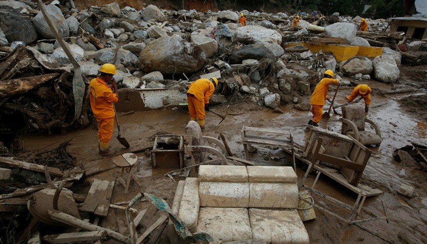 Rescuers look for bodies in a destroyed area, after flooding and mudslides caused by heavy rains