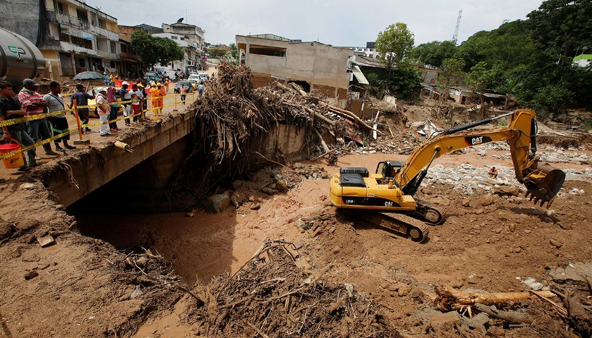 An excavator works by taking stones from the river, after flooding and mudslides caused by heavy rai