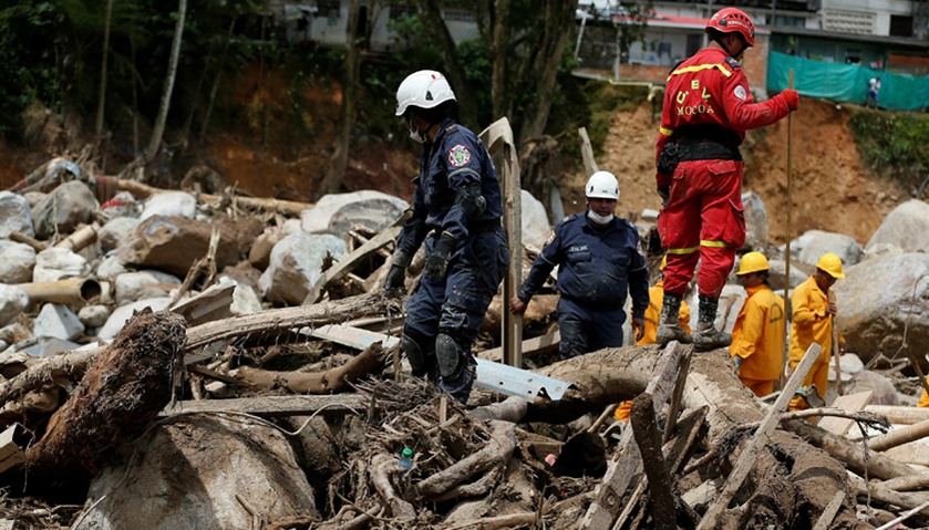 Rescuers look for bodies in a destroyed area after flooding and mudslides caused by heavy rains in M