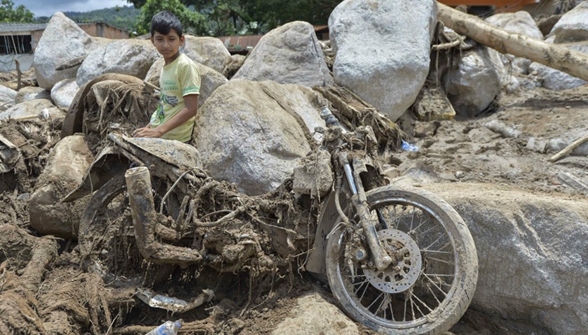 A boy sits next to a motorcycle destroyed by the mudslides in Mocoa, southern Colombia