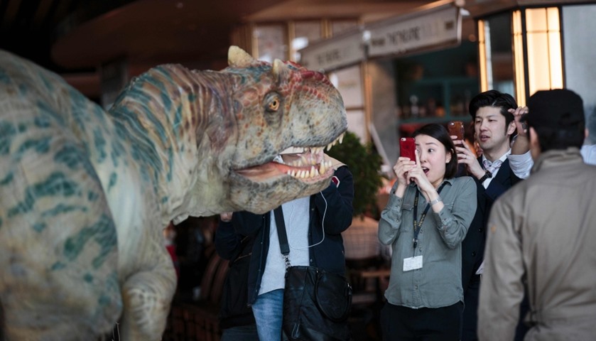 A woman takes pictures of dino-tronics during a performance