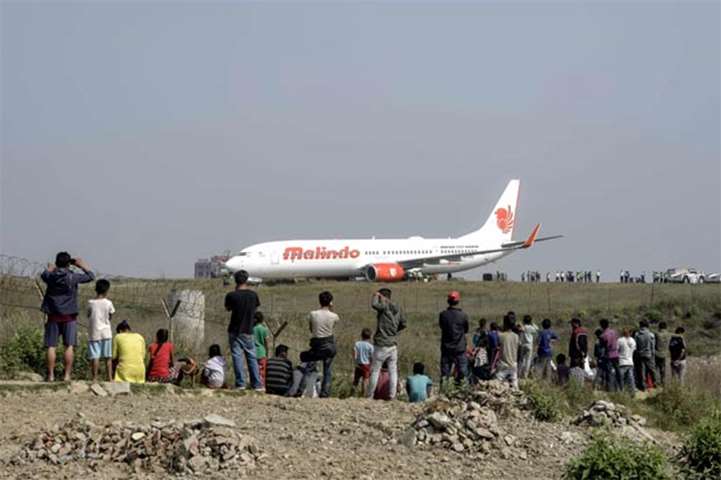 Onlookers watch workers try to bring a Malindo Air jet back onto the runway in Kathmandu on Friday