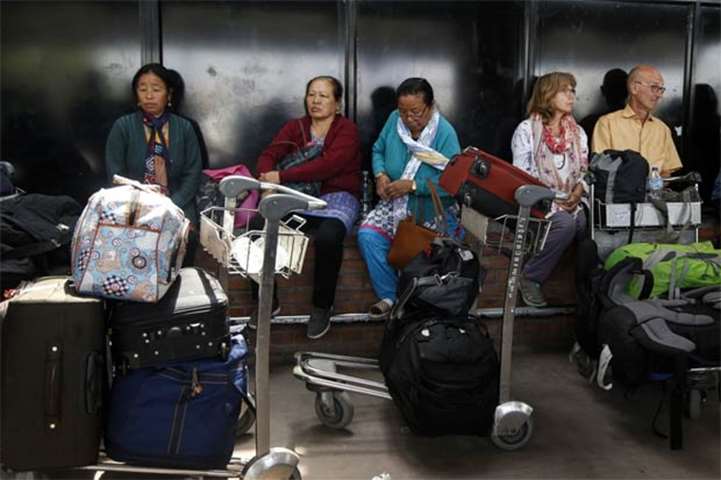 Stranded travellers sit outside the Kathmandu international airport on Friday