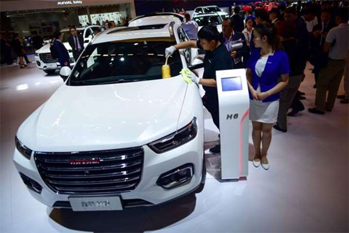 A staff member cleans a Haval H6 car on display at the Beijing auto show