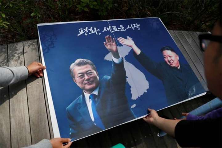 Students hold posters with pictures of Moon Jae-in and Kim Jong Un during a rally in Seoul