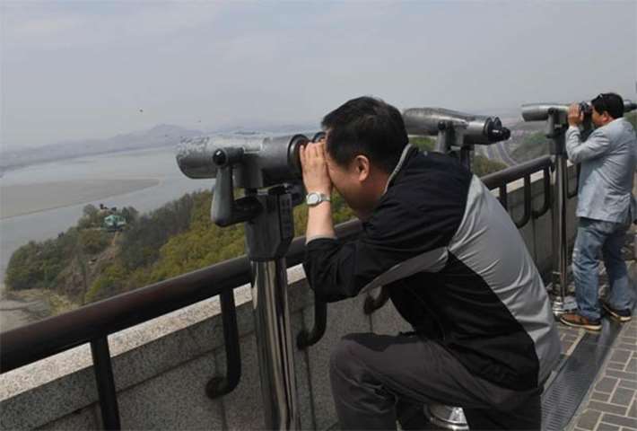 Visitors look towards North Korea through binoculars at an observatory in Paju, South Korea