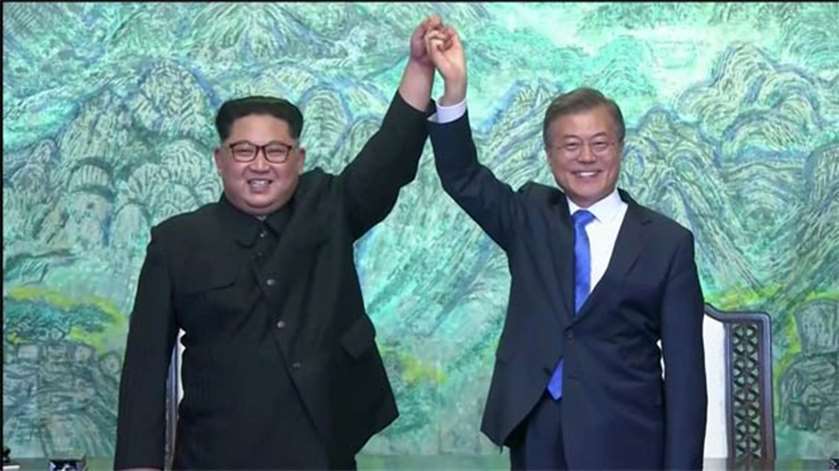 North Korean leader Kim Jong Un and South Korean President Moon Jae-in gesture after signing accords