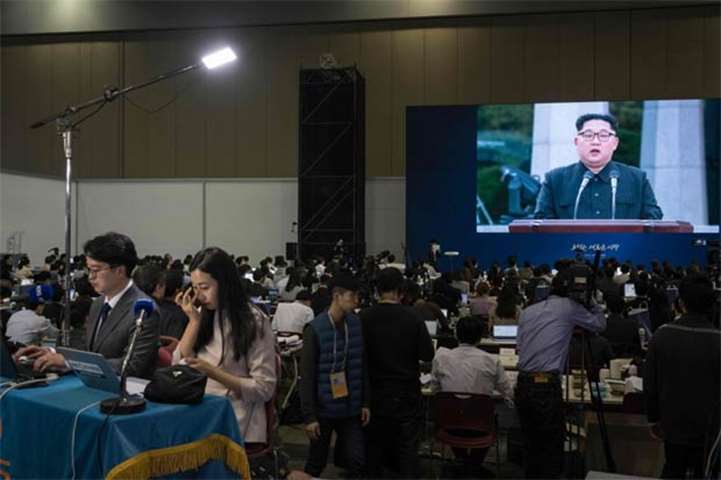 A screen shows coverage of a statement being read by Kim Jong Un at the summit media centre