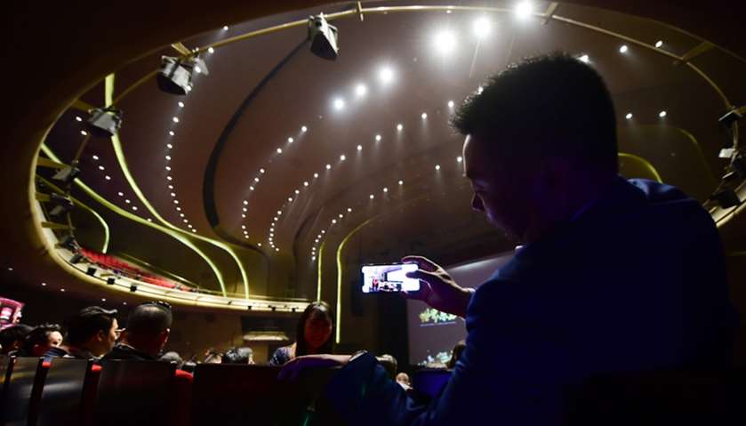 A guest takes pictures using his mobile phone before opening ceremony of the Wanda Qingdao Movie Met