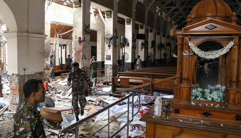 Sri Lankan security personnel walk past debris at St. Anthony's Shrine following an explosion