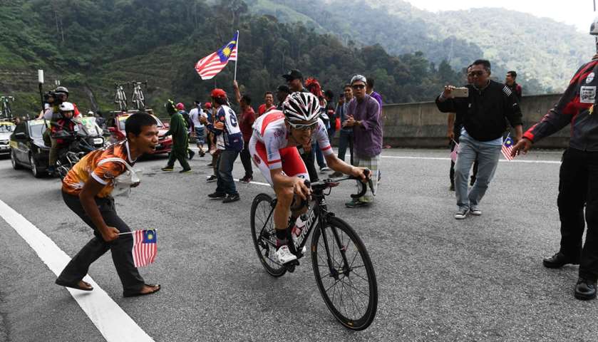 Spectators cheer as cyclists ride uphill in Genting Highlands
