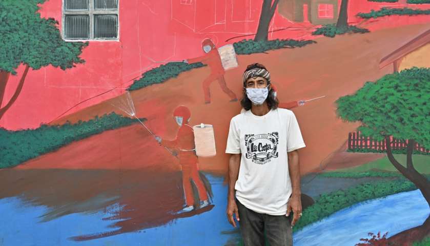 Mural artist Dache Samant posing with his artwork
