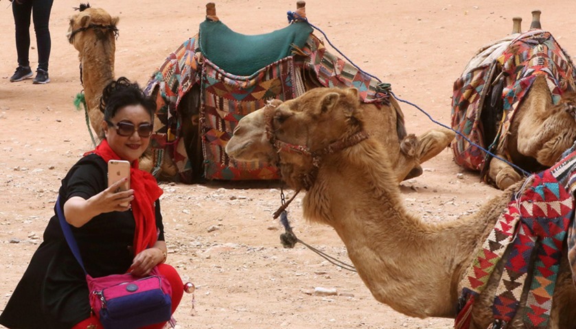 A tourist takes a selfie with a camel in the ancient city of Petra in Jordan