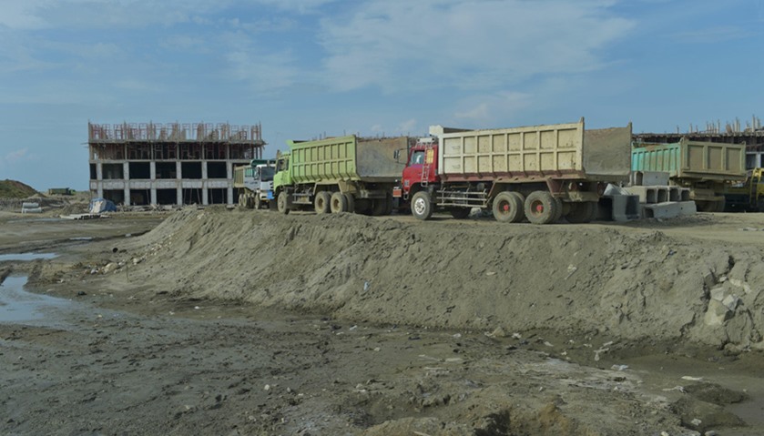 Trucks park next to an unfinished building on a man-made islet known as the giant sea wall projects