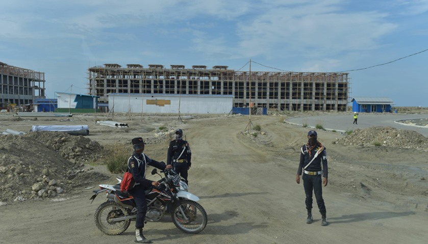 Indonesian security personnels stand next to newly built business center on a man-made islet