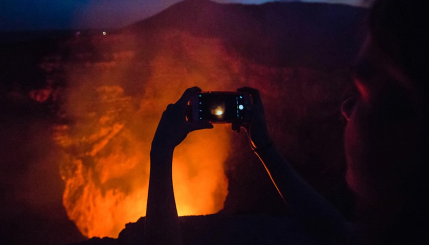 Tourists take pictures of a lava lake inside the crater of the Masaya Volcano in Masaya