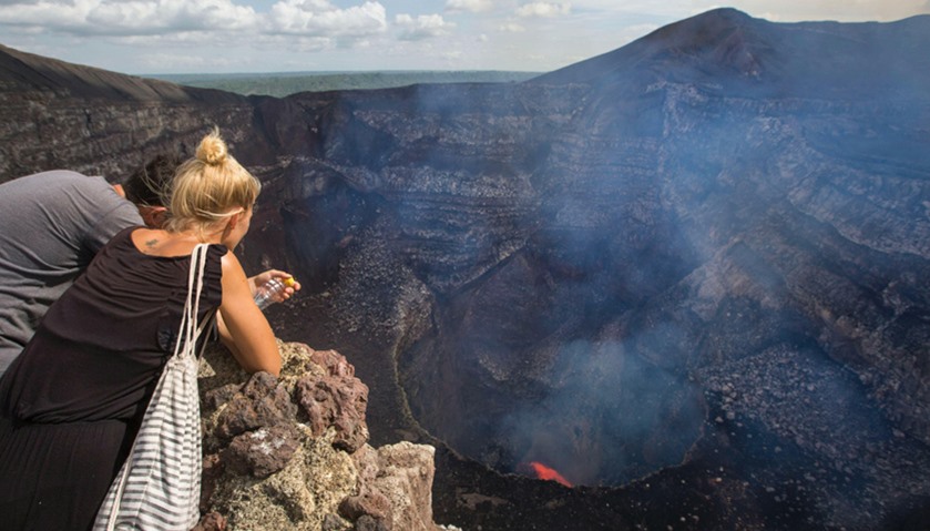 Tourists watch a lava lake inside the crater of the Masaya Volcano in Masaya