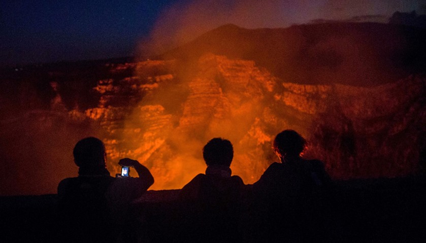 Tourists take pictures of a lava lake inside the crater of the Masaya Volcano in Masaya